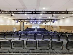 een leeg auditorium met blauwe stoelen en een podium bij Novotel Paris Est in Bagnolet