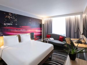 um quarto de hotel com uma cama grande e uma secretária em Novotel Bordeaux Centre Ville em Bordeaux