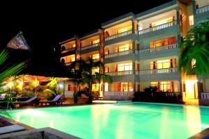 a hotel with a swimming pool in front of a building at Nightingale Apartments Hotel Mombasa in Shanzu