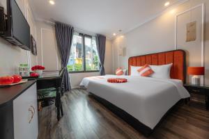 Omina Hanoi Hotel & Travel في هانوي: غرفة نوم مع سرير أبيض كبير ومكتب