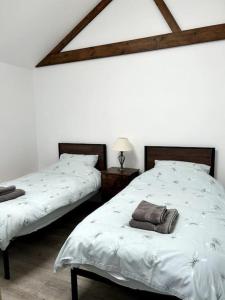 um quarto com 2 camas e lençóis brancos em The Dairy em Sutton