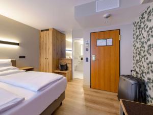 a hotel room with a bed and a wooden door at Mercure Hotel München Altstadt in Munich