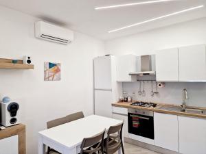a kitchen with white cabinets and a white table and chairs at Tower Apartments in Terracina