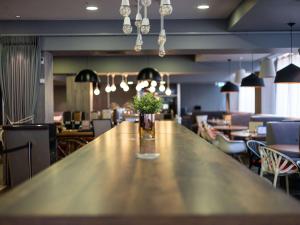 a long wooden table with a vase of flowers on it at ibis London City - Shoreditch in London