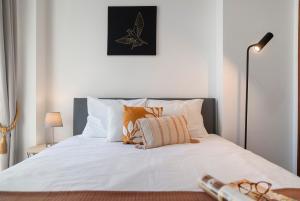 ein Schlafzimmer mit einem Bett mit weißen Laken und orangefarbenen Kissen in der Unterkunft Apartamento do Carmo by An Island Apart in Funchal