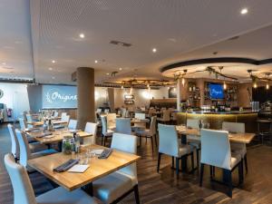 um restaurante com mesas e cadeiras de madeira e um bar em Novotel Luxembourg Centre em Luxemburgo