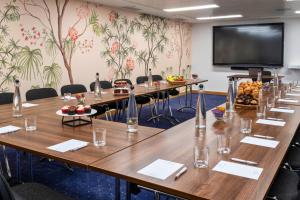 a conference room with tables and a large screen at St Giles London – A St Giles Hotel in London