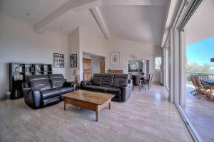 a living room with black leather furniture and a table at FRGK "Villa Le Petit Bois Vue Panoramique Jardin Verdoyant près de Cannes" in Vallauris