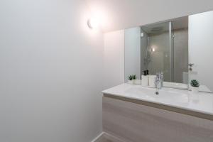 ein Badezimmer mit einem weißen Waschbecken und einem Spiegel in der Unterkunft Host Wise - Central Duplex House - Terrace in Vila Nova de Gaia