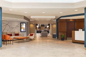 Embassy Suites by Hilton Kansas City Overland Park في أوفرلاند بارك: لوبي مستشفى فيه كراسي وطاولات