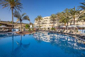 una gran piscina con palmeras y edificios en Barceló Corralejo Bay - Adults Only, en Corralejo