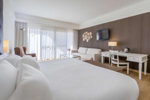 a hotel room with a white bed and a desk at Barceló Corralejo Bay - Adults Only in Corralejo