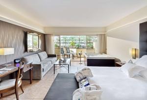 a hotel room with a large bed and a living room at Barceló Corralejo Bay - Adults Only in Corralejo