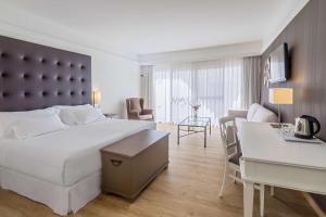 a hotel room with a large bed and a desk at Barceló Corralejo Bay - Adults Only in Corralejo