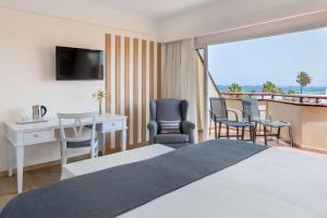 a hotel room with a bed and a desk and chairs at Barceló Corralejo Bay - Adults Only in Corralejo