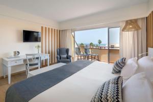 a hotel room with a large bed and a balcony at Barceló Corralejo Bay - Adults Only in Corralejo