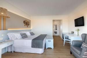a bedroom with a bed and a desk and a chair at Barceló Corralejo Bay - Adults Only in Corralejo