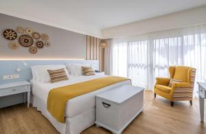 a bedroom with a large bed and a chair at Barceló Corralejo Bay - Adults Only in Corralejo