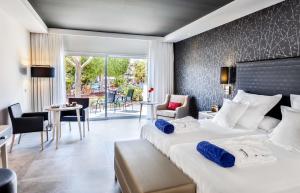 a hotel room with two beds and a table and chairs at Barceló Corralejo Bay - Adults Only in Corralejo