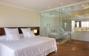 a bedroom with a white bed and a glass shower at Barceló Corralejo Bay - Adults Only in Corralejo