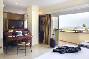 a hotel room with a desk and a television at Barceló Corralejo Bay - Adults Only in Corralejo