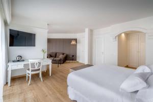 a white hotel room with a bed and a desk at Barceló Corralejo Bay - Adults Only in Corralejo