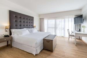 a bedroom with a large white bed and a desk at Barceló Corralejo Bay - Adults Only in Corralejo