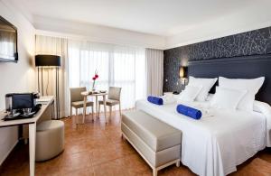 a hotel room with a large bed and a desk at Barceló Corralejo Bay - Adults Only in Corralejo