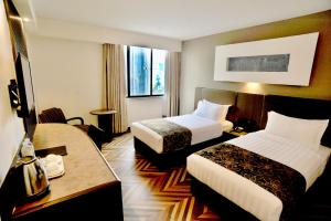 Habitación de hotel con 2 camas y escritorio en REGALPARK Hotel Kuala Lumpur, en Kuala Lumpur