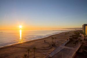 a view of a beach with the sun rising over the ocean at El Séptimo Cielo de la Bahía de los Naranjos - Primera Línea de Playa in Cullera