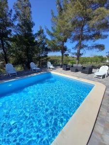 a swimming pool with chairs and trees in the background at Los Pinos Munera in Munera
