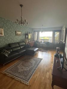uma sala de estar com um sofá de couro preto e uma televisão em Lakeview central residence em Savonlinna