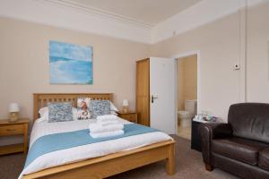 a bedroom with a bed and a leather chair at Epchris House in Ilfracombe