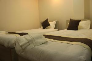 a room with two beds with white sheets and brown pillows at Hotel Junction in Kathmandu