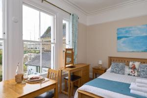 a bedroom with a bed and a desk and a window at Epchris House in Ilfracombe