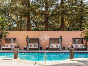 a pool with two beds next to a wall with trees at Fairmont Sonoma Mission Inn & Spa in Sonoma