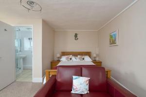 a bedroom with a bed and a red chair at Epchris House in Ilfracombe