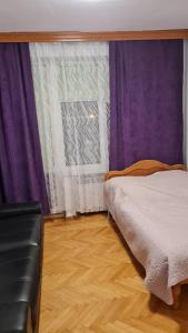 1 dormitorio con cortinas moradas, 1 cama y suelo de madera en Pensjonat AIDA, en Ciechocinek