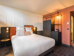 Pokój hotelowy z dużym białym łóżkiem z poduszkami w obiekcie Mercure Bordeaux Centre Gare Atlantic w mieście Bordeaux