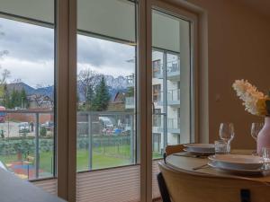 a dining room with a table and a large window at VacationClub - Apartamenty Zakopiańskie Apartament 112 in Zakopane