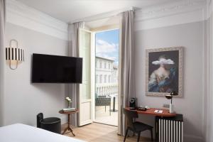 ein Hotelzimmer mit einem Bett, einem Schreibtisch und einem Fenster in der Unterkunft Anglo American Hotel Florence, Curio Collection By Hilton in Florenz
