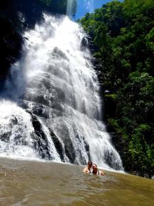 two people swimming in the water in front of a waterfall at Elangeni Holiday Resort in Waterval Boven