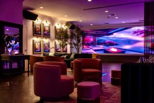 a bar with red chairs and a large screen at Hotel NoMa, Trademark Collection by Wyndham in New Rochelle