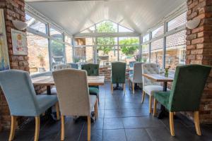 a dining room with tables and chairs and windows at Harmony House Boutique B&B in Stillingfleet