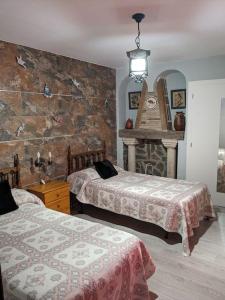 a bedroom with two beds and a stone wall at Casa Rural Maire in Gata