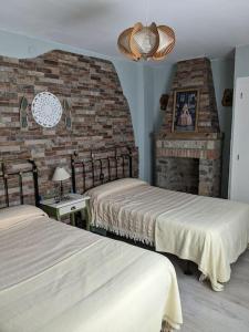1 dormitorio con 2 camas y pared de ladrillo en Casa Rural Maire, en Gata