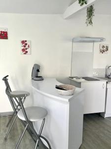 una cocina blanca con encimera y 2 taburetes en Casa 4 Saisons - Studio - Piscine et Jardin - Brive, en Brive-la-Gaillarde