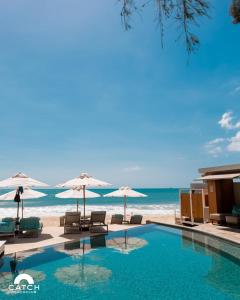 una piscina junto a la playa con sombrillas en Perfect 2br Pool Villa In Residence Bangtao Beach4, en Bang Tao Beach