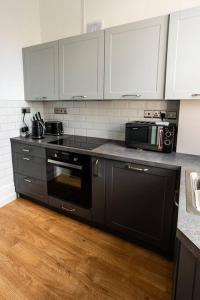 een keuken met een zwarte kachel en een magnetron bij Studio Coastal Escape Apartment 2 in Christchurch