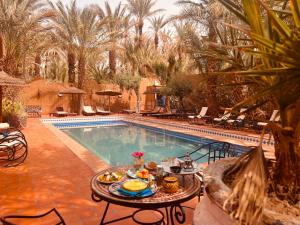 stół z jedzeniem obok basenu w obiekcie Riad le petit jardin w mieście Zakura